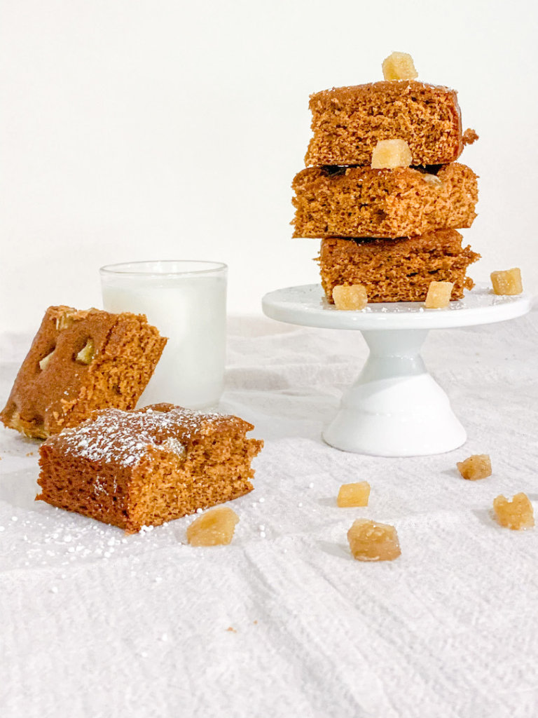 Squares of gingerbread cake on a pedestal with a cup of milk