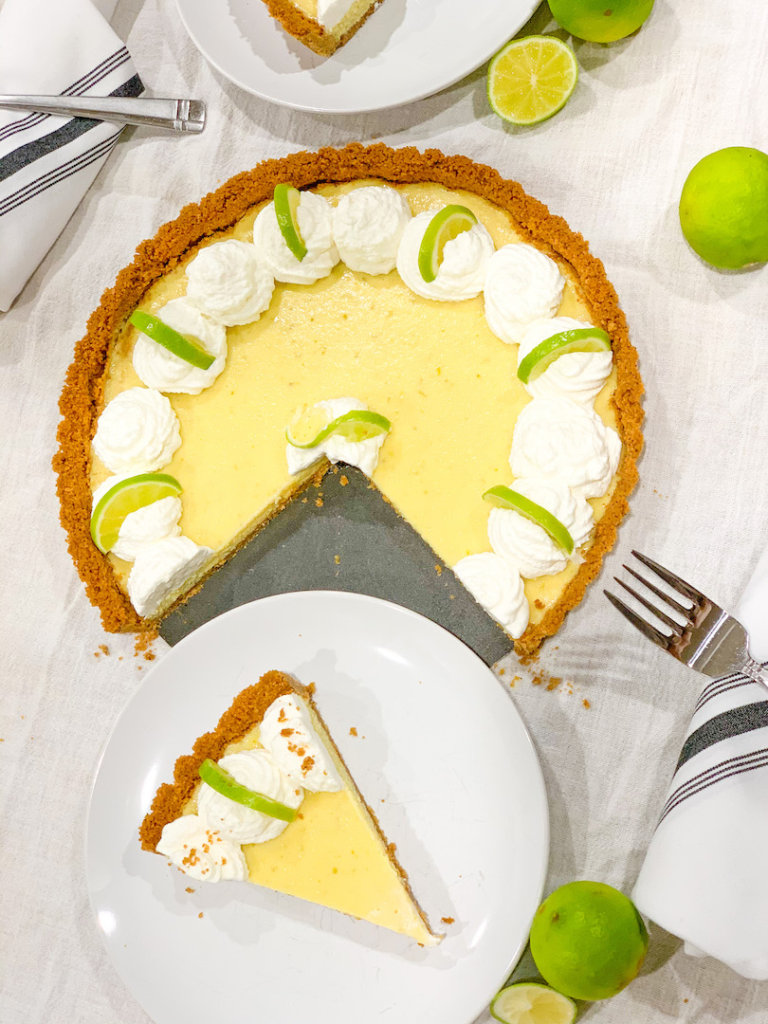 A slice of key lime tart served from the whole tart