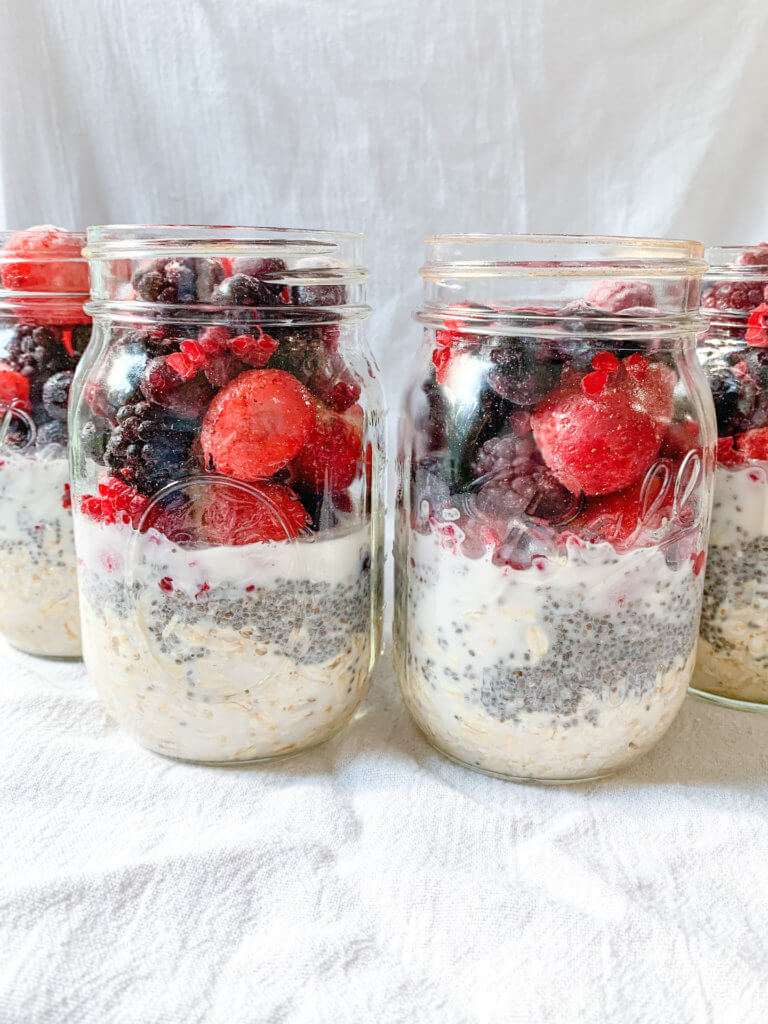 Ball jars filled with oats, chia seeds, almond milk and frozen berries.