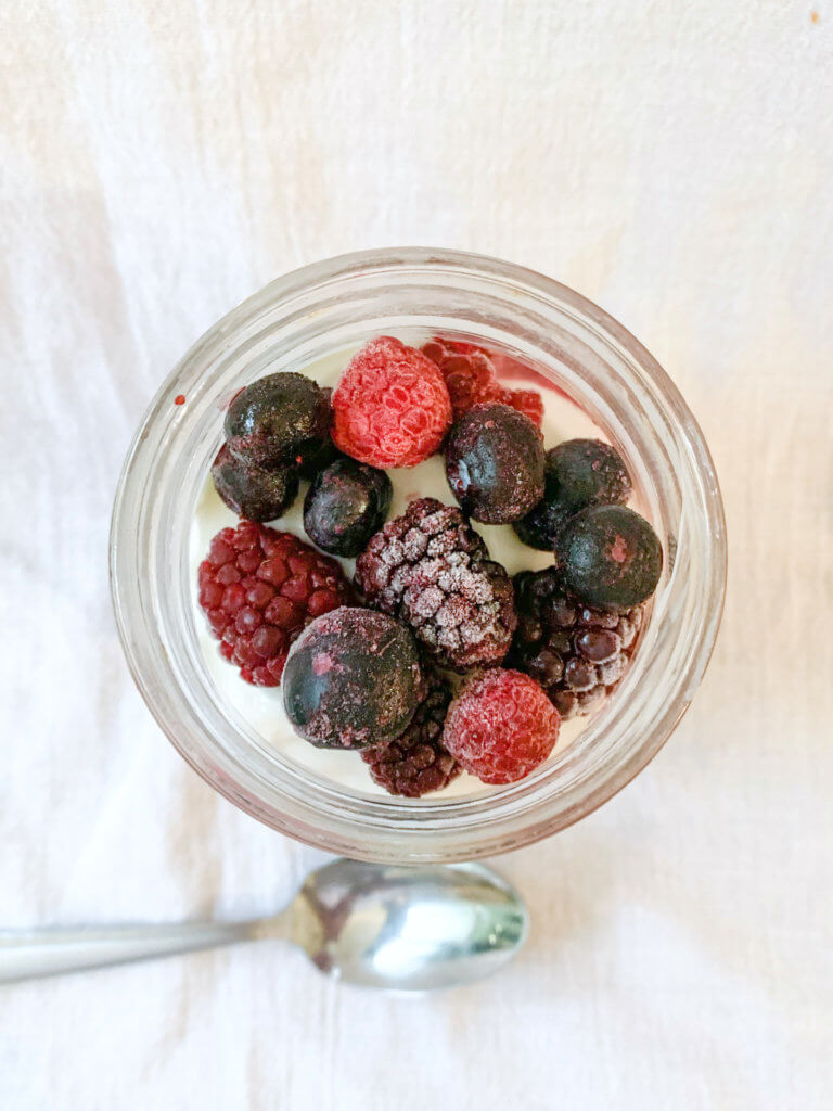 Top view of berry chia overnight oats topped with greek yogurt and frozen mixed berries