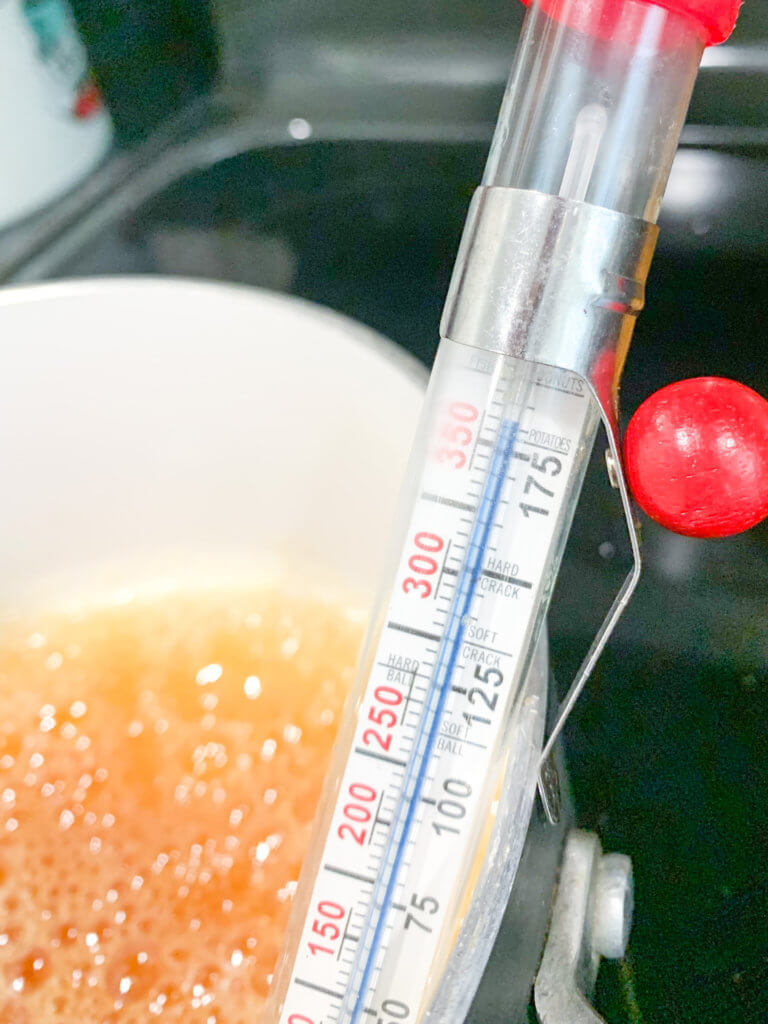 Candy thermometer showing over 350ºF on a pot of amber caramel
