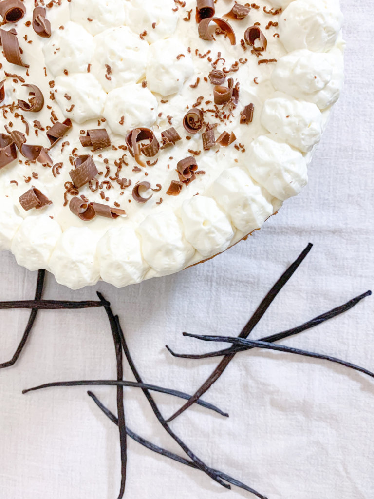 Grade A Bourbon Vanilla Beans from Java, Indonesia beside vanilla bean cheesecake topped with chocolate shavings