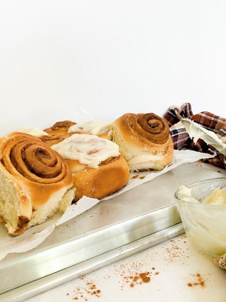 Side view of cinnamon rolls with offset spatula of frosting on the side