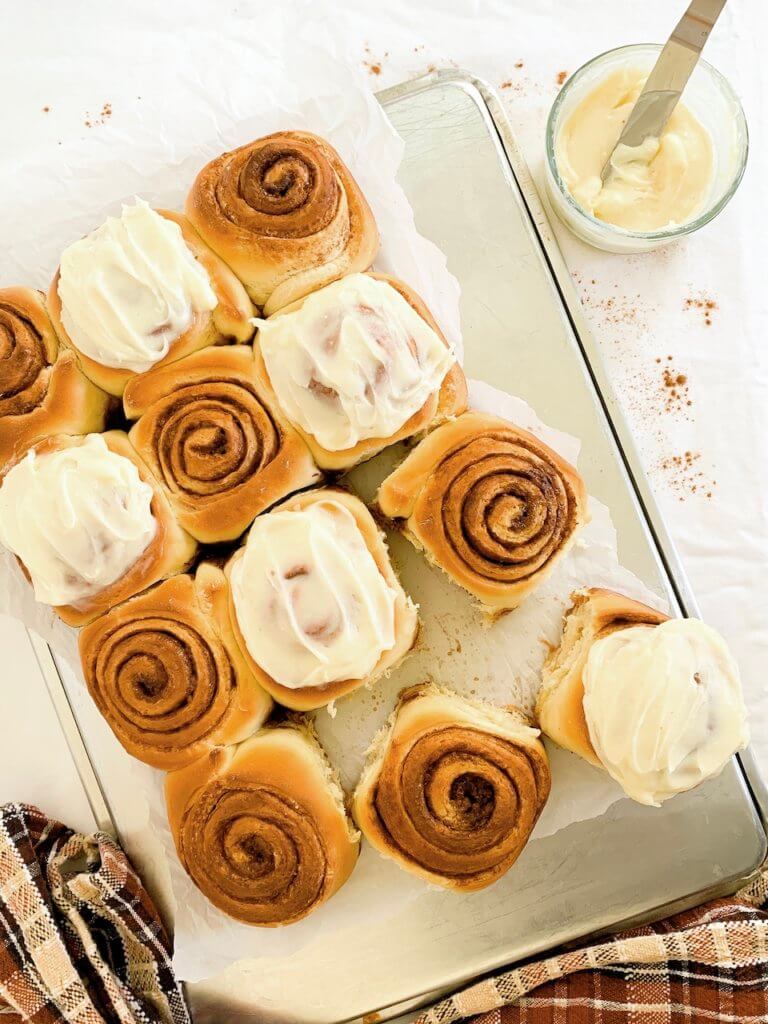 Overhead shot of golden, perfectly swirled cinnamon rolls with cream cheese frosting