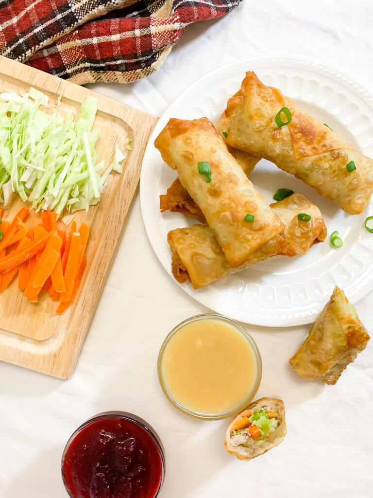 Overhead shot of egg rolls with one cross section, and dips