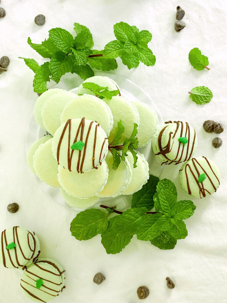 Overhead shot of peppermint cocoa macarons with mint and chocolate chips around
