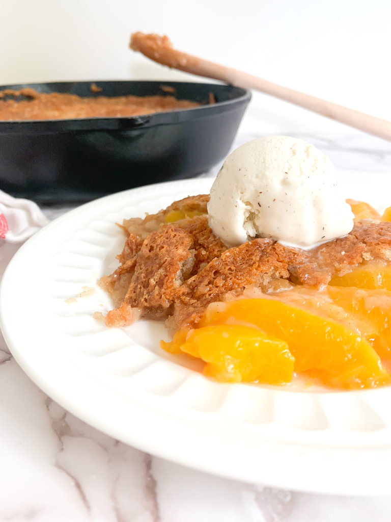 Close up of peach cobbler with a scoop of vanilla ice cream on top