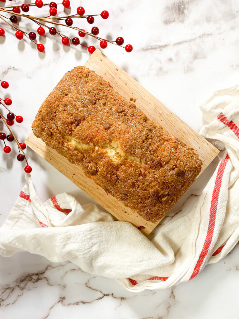 Cinnamon Cranberry Coffee Cake on a wood cutting board with a dish towel.