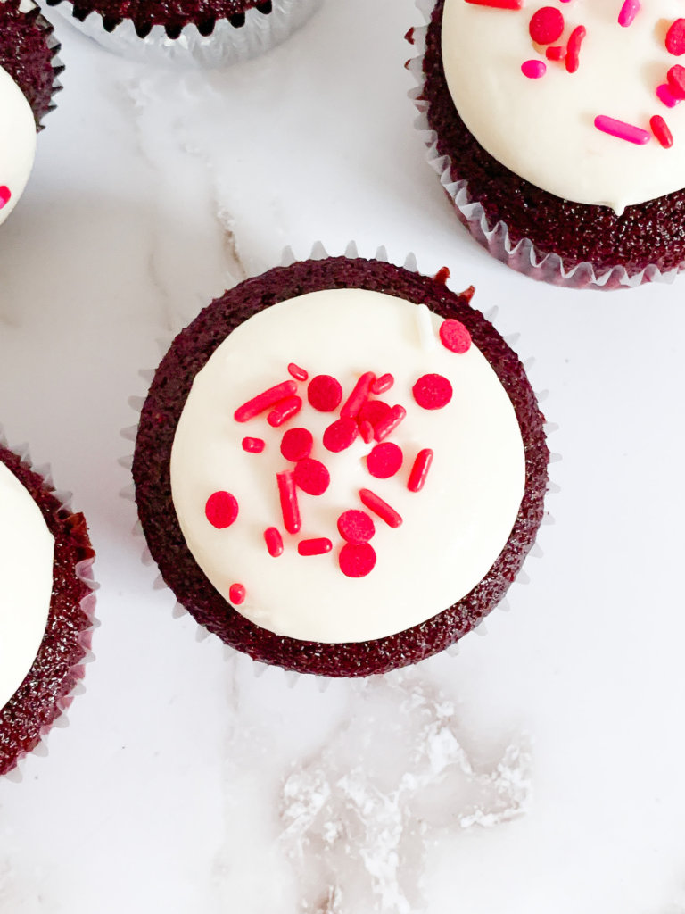 red velvet cupcake with cream cheese frosting and red sprinkles