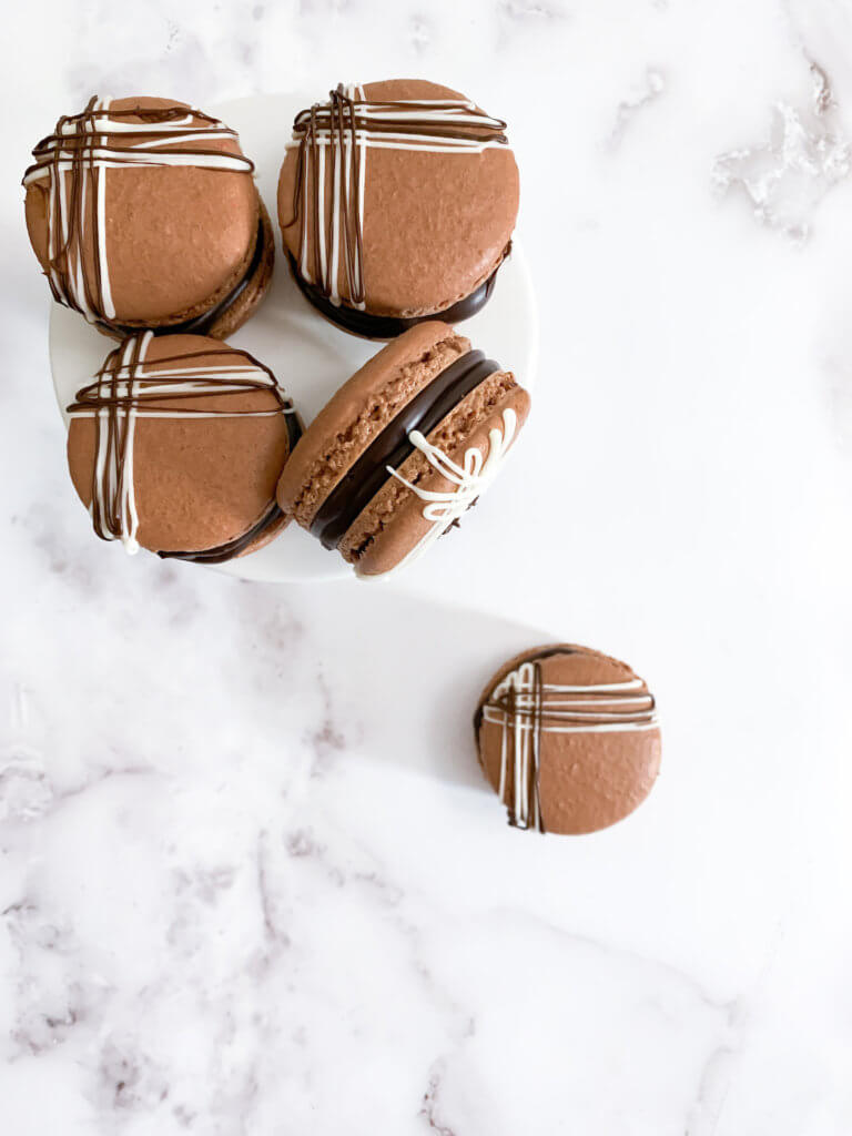 Chocolate almond macarons on a pedestal on a white counter
