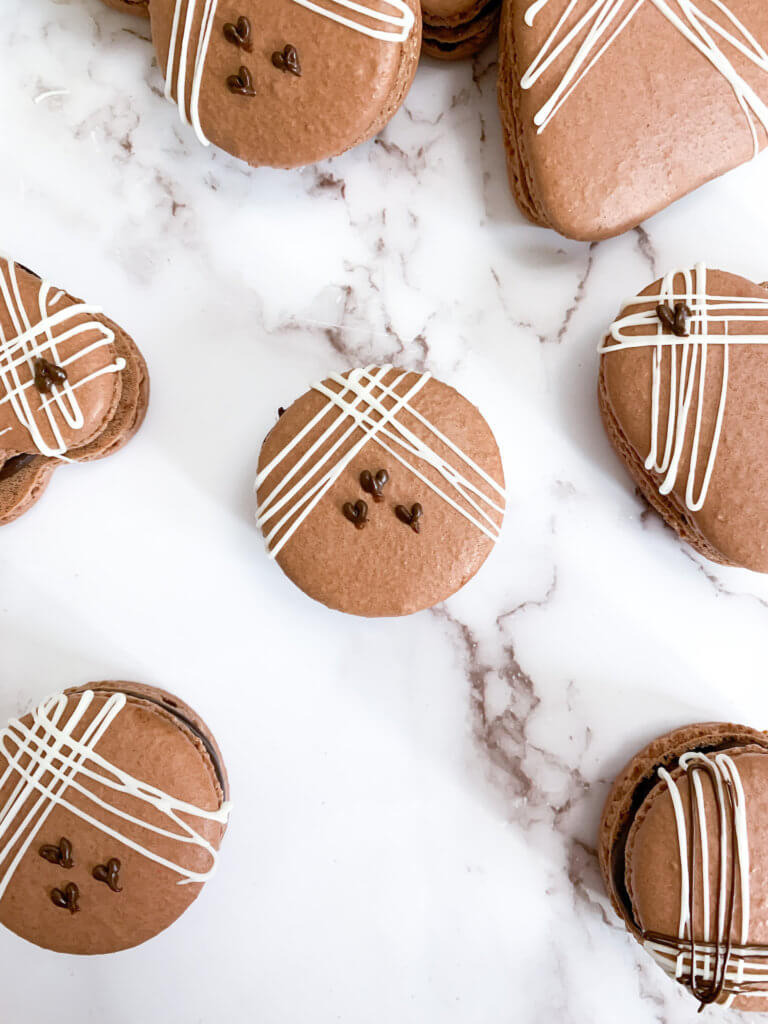 decorated chocolate almond macarons on a white counter