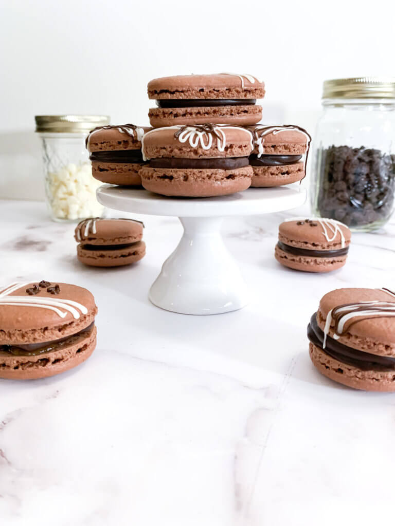 chocolate almond macarons on a pedestal on a white counter