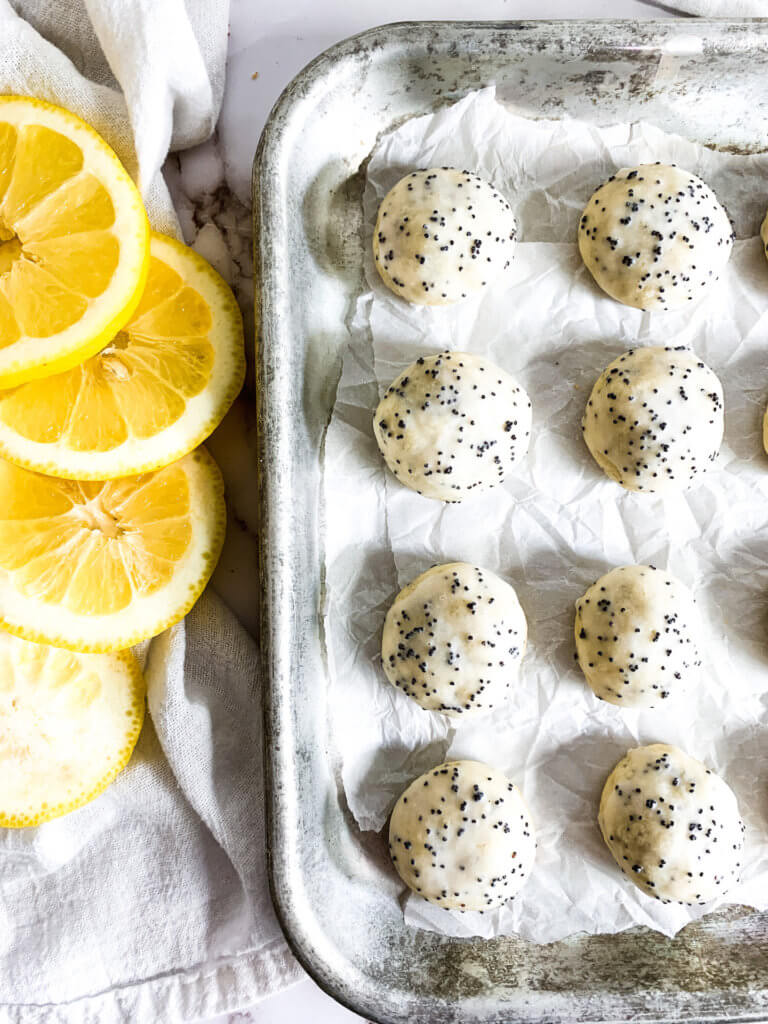 a tray of lemon poppyseed cookies next to sliced lemons
