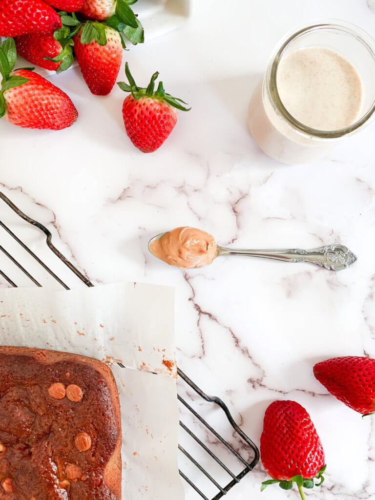 Strawberries, peanut butter, sourdough starter and blondies on a white counter