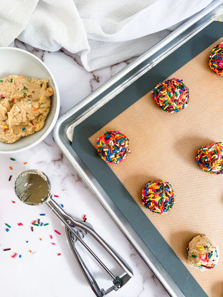 Scooped sprinkle cookies on a baking sheet