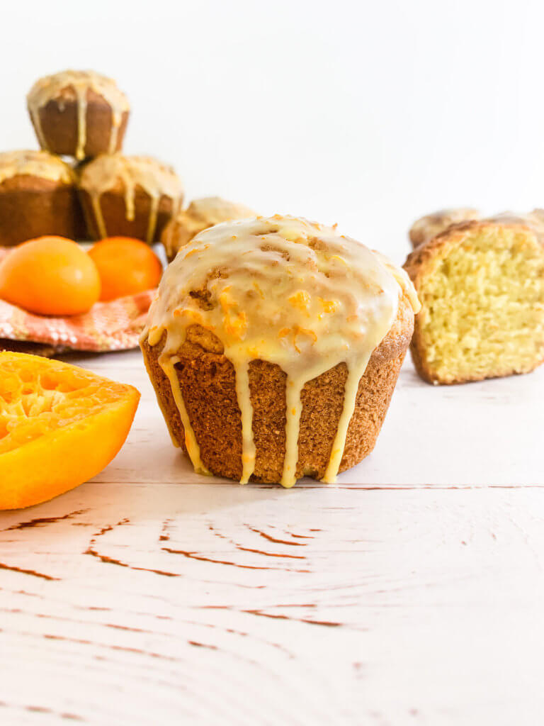 Closeup of a glazed clementine muffin with glaze dripping down the side.