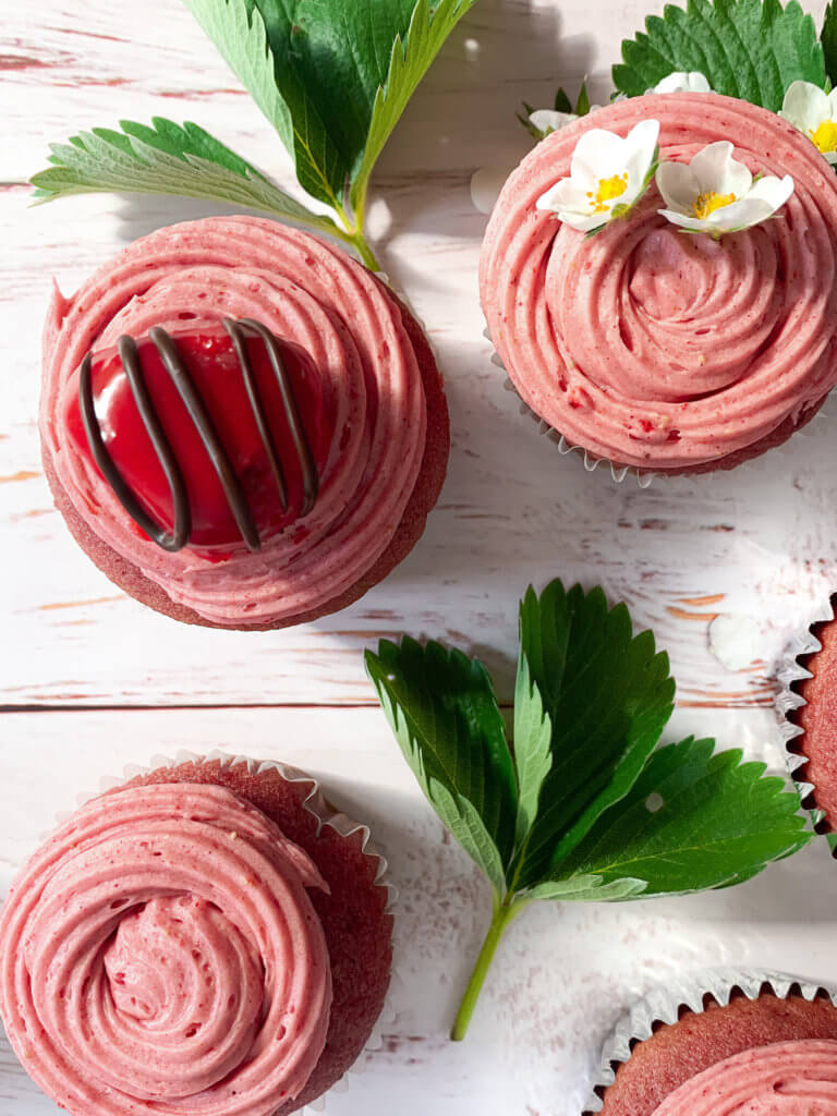 strawberry cupcakes with a chocolate drizzled strawberry cake pop bite on top