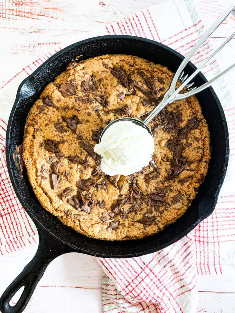 Chocolate chunk skillet cookie in a cast iron skillet with a scoop of vanilla ice cream on top
