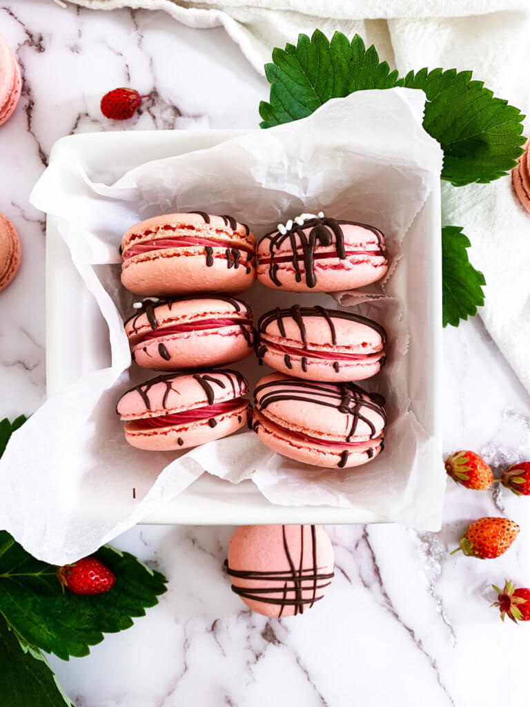 berry basket full of chocolate drizzled strawberry cheesecake macarons