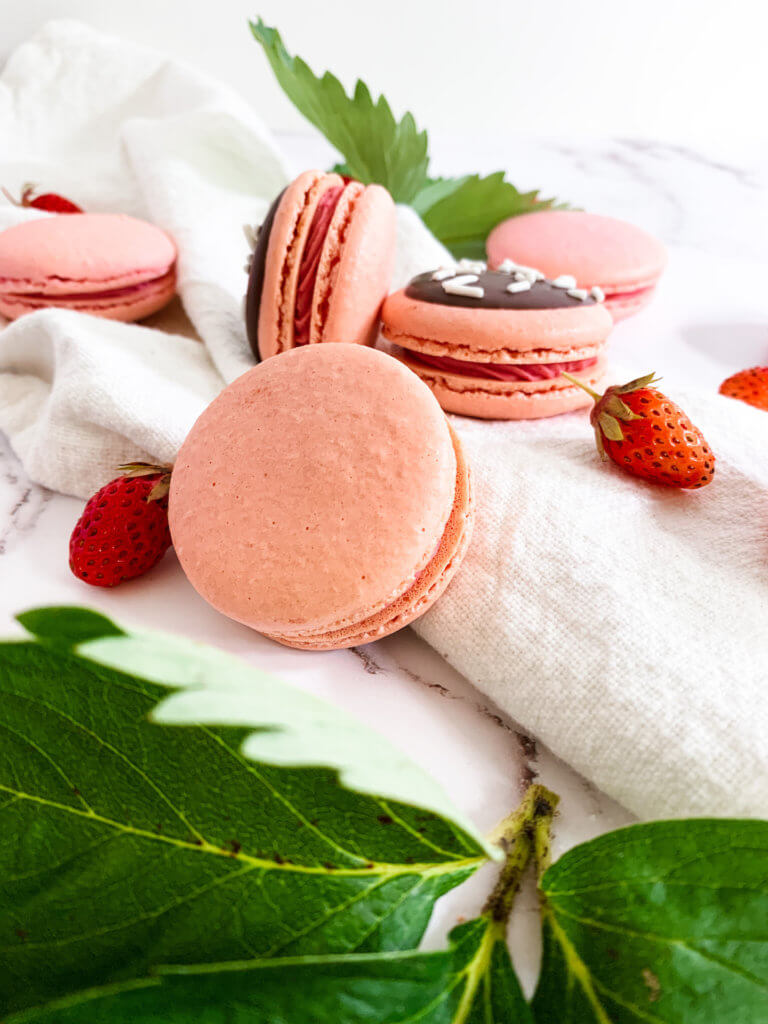strawberry cheesecake macarons with strawberries and berry leaves