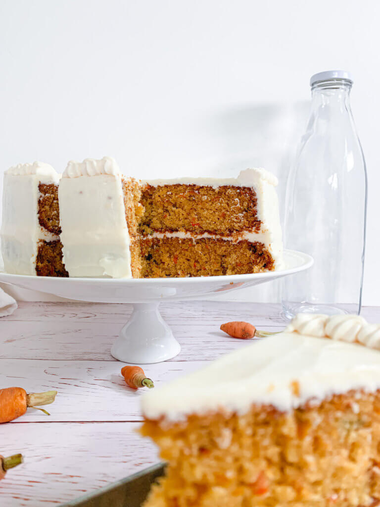 Sliced carrot cake revealing two layers with a layer of cream cheese frosting in the middle