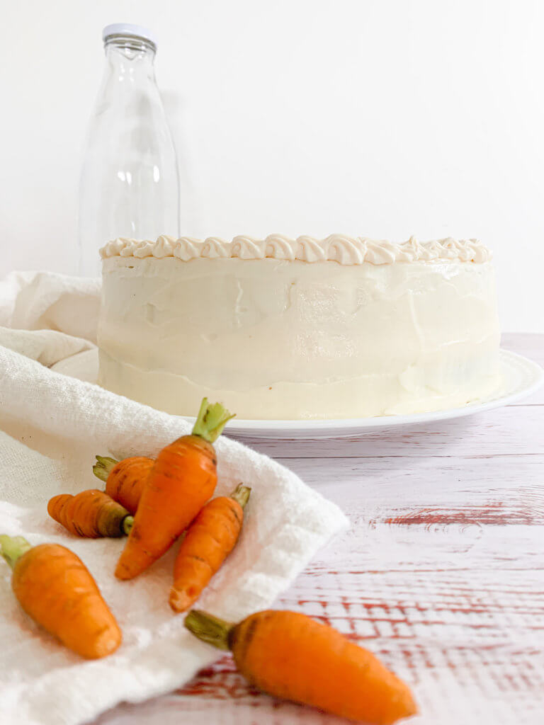 Front view of carrot cake with pile of baby carrots