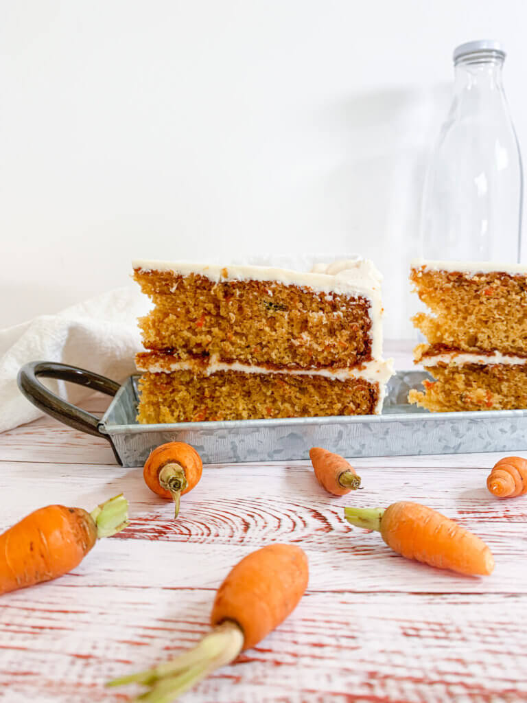 Perfect slices of carrot cake on a steel tray with baby carrots in front