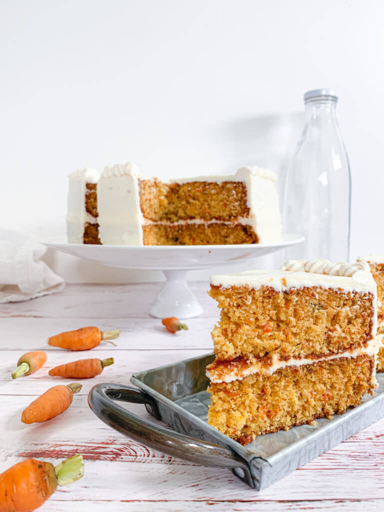 Clean slice of carrot cake on a steel tray with baby carrots