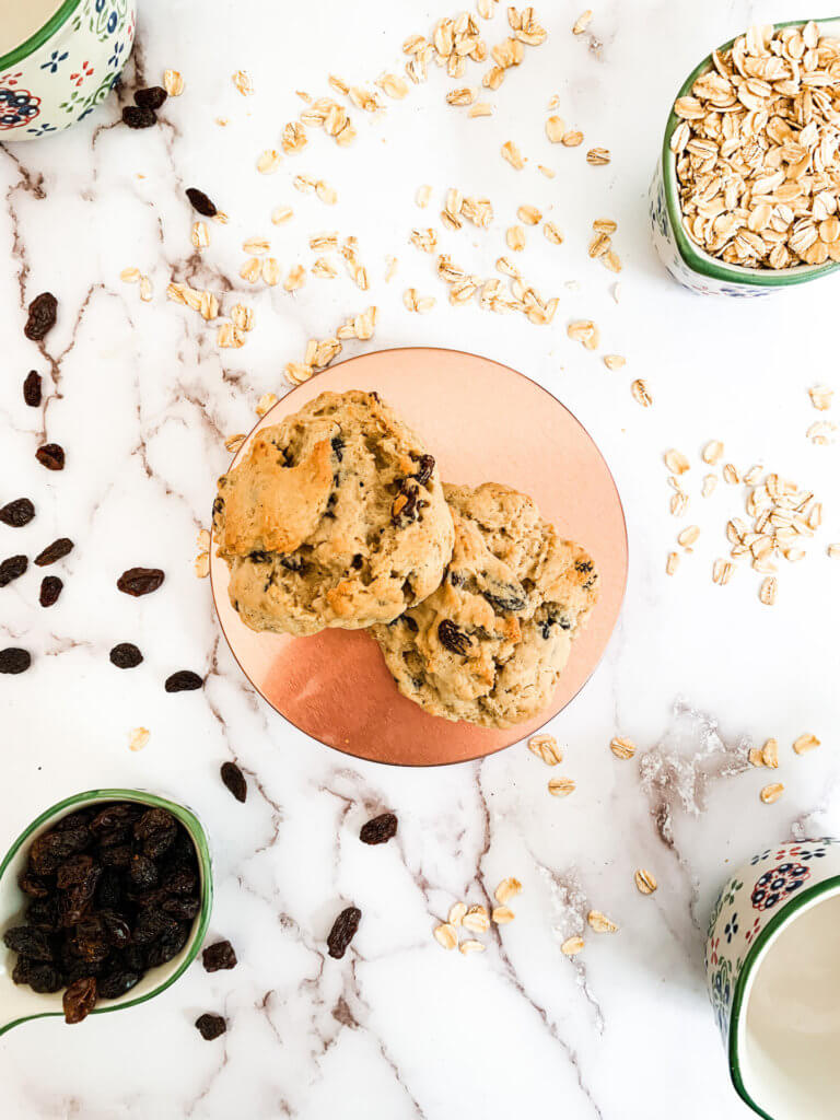 Oatmeal raisin cookies for two on a copper plate surrounded by oats and raisins.