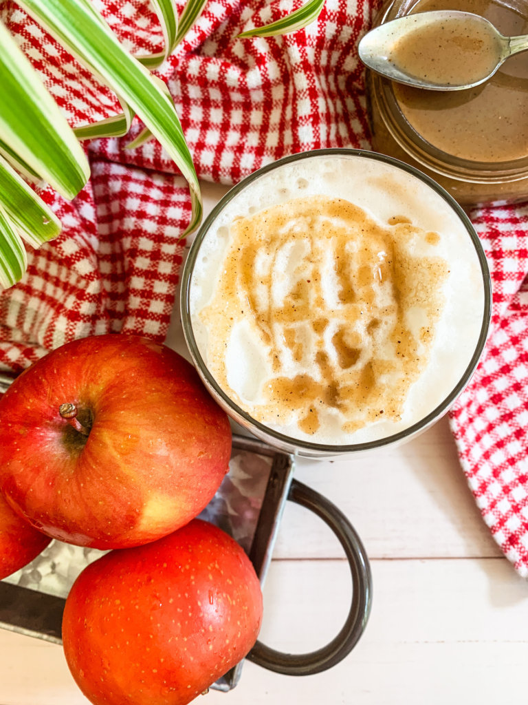 fresh apples and a spicer plant next to an apple crisp macchiato drizzled with spiced apple caramel