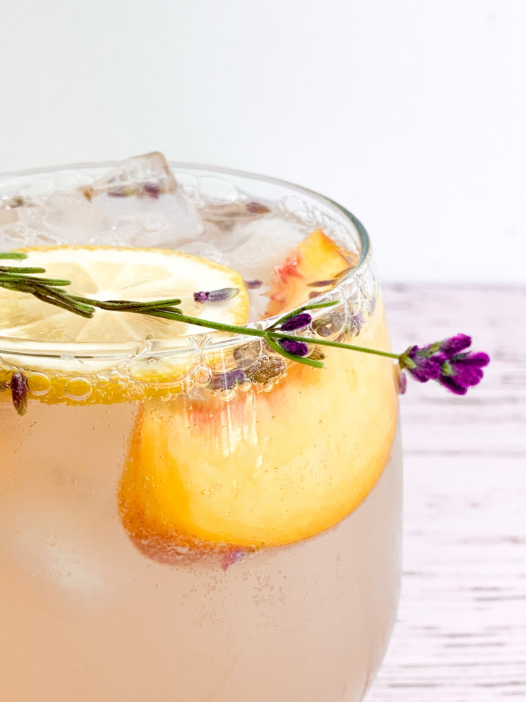 close up of fizzy bubbles around a peach and lavender garnish in a glass of peach lavender lemonade spritzer