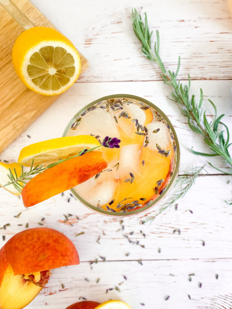 overhead glass of peach lavender lemonade spritzer with a sprig of lavender