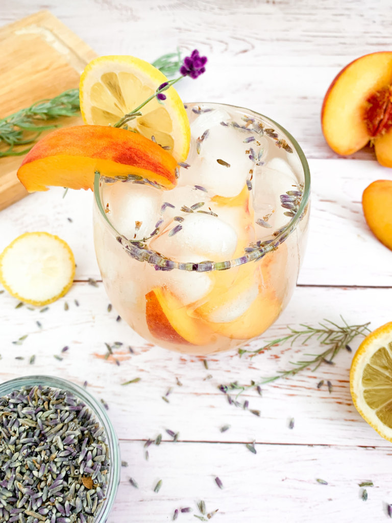 peach lavender lemonade with lavender buds, and a garnish of peach and lemon slices