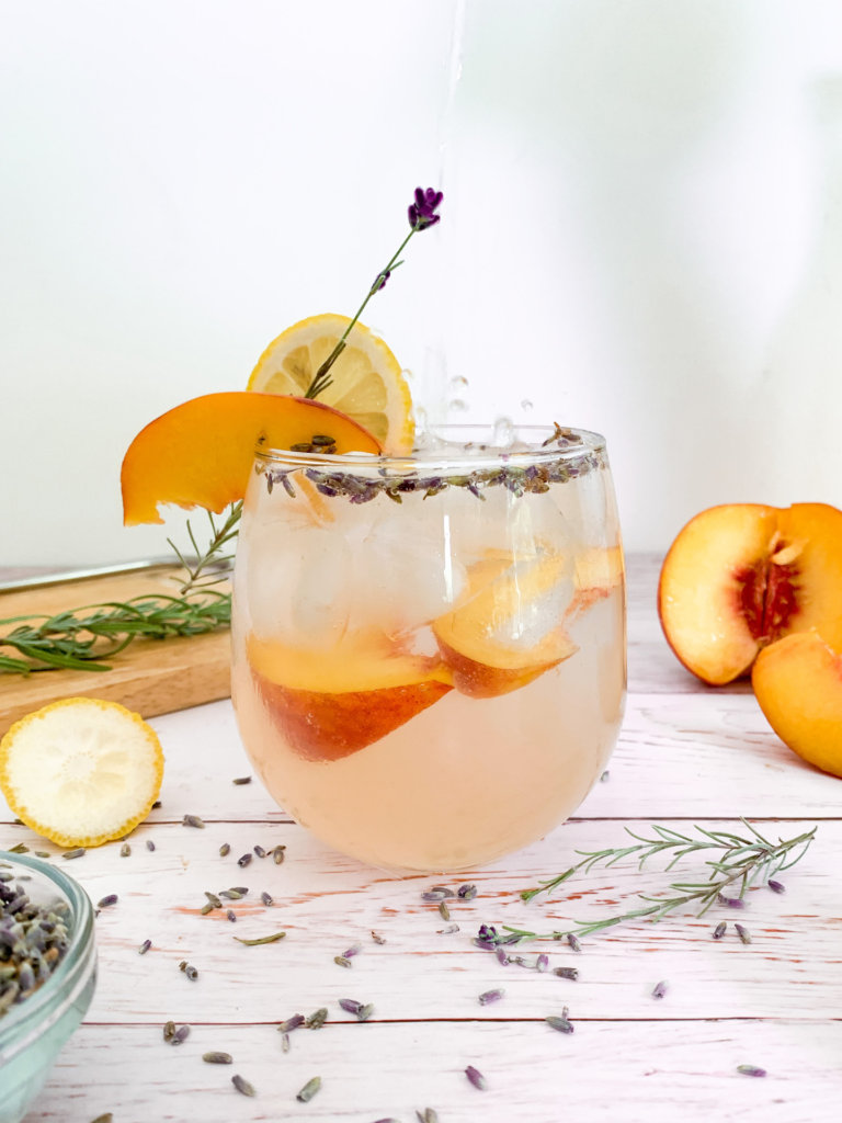 seltzer being poured into a glass of peach lavender lemonade with a bit of splash