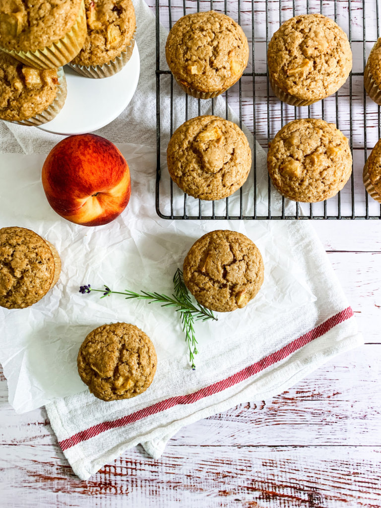 Peach muffins with lavender sprigs on a white and red dish towel