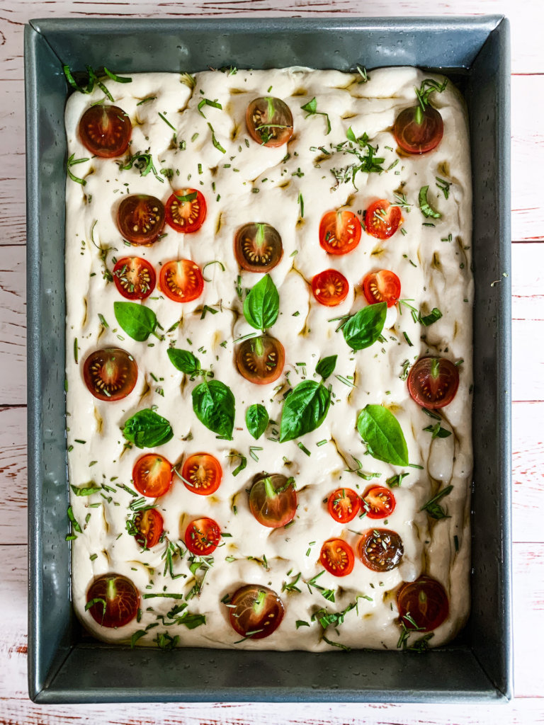 Raw sourdough focaccia studded with cherry tomatoes, basil and rosemary.