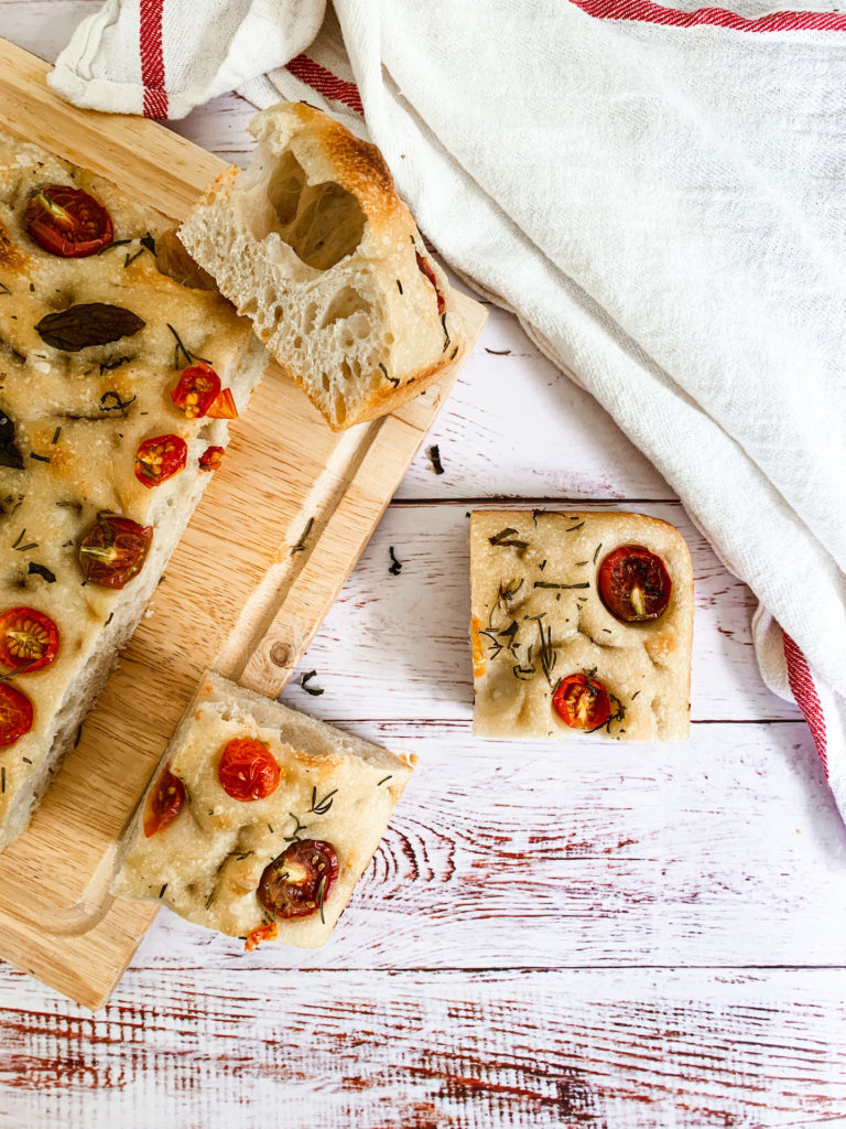 tomato and herb sourdough focaccia slices on a white washed counter