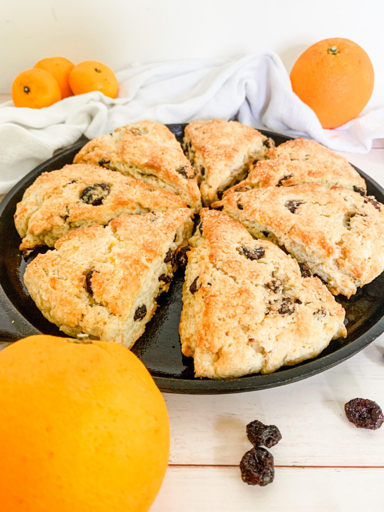 cranberry orange scones on a cast iron skillet with oranges and dried cranberries
