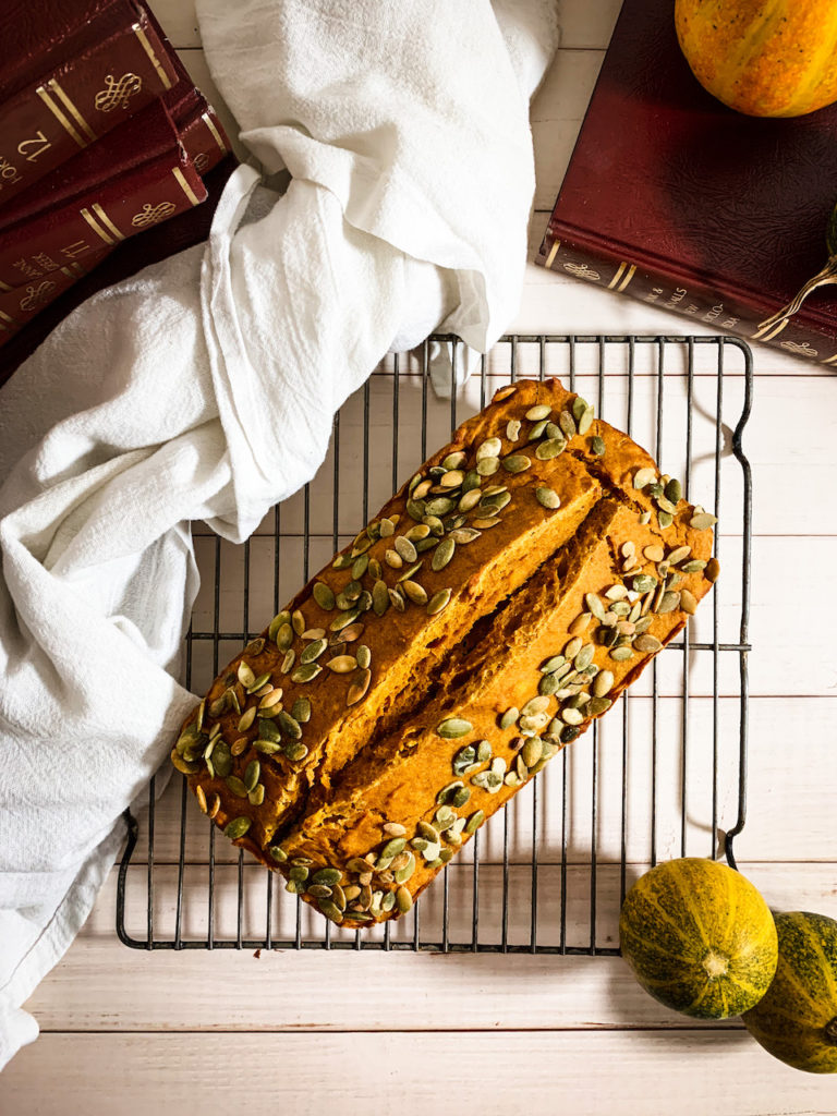 pumpkin bread on a cooling rack with baby pumpkins