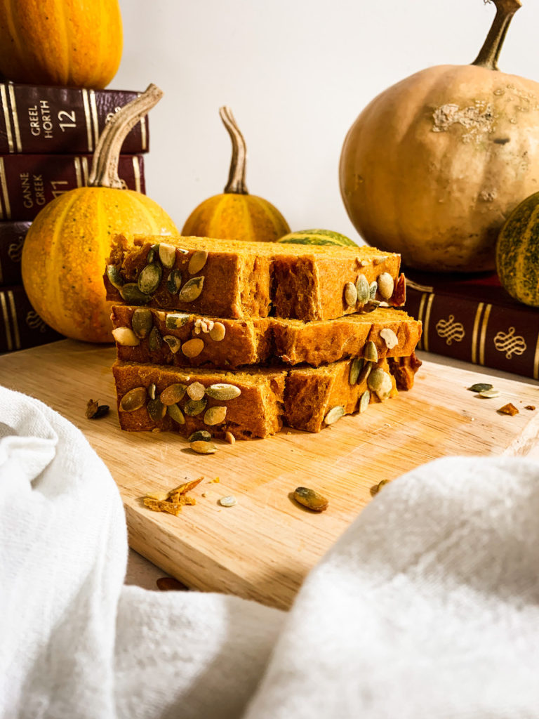 three slices of maple pumpkin bread stacked on a wood cutting board