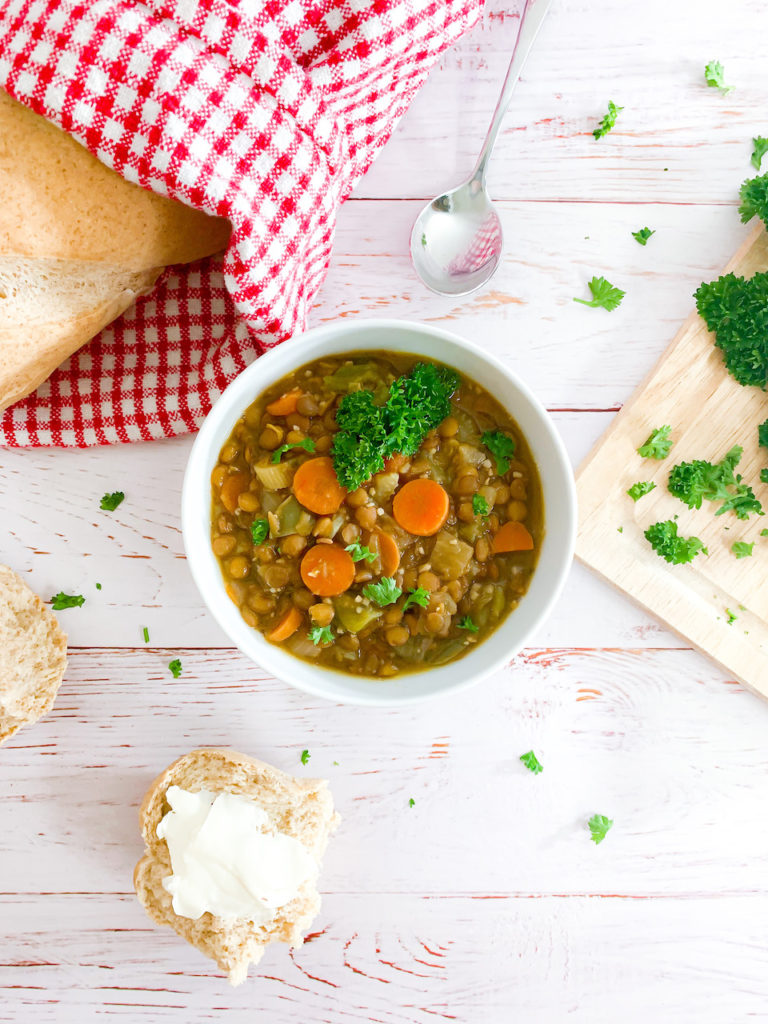 Overhead of french lentil soup with parsley and a torn up baguette