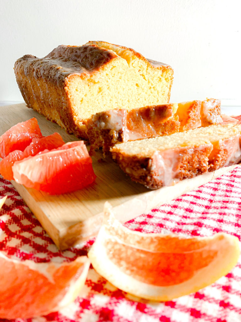 grapefruit pound cake on a cutting board with slices of grapefruit and peels